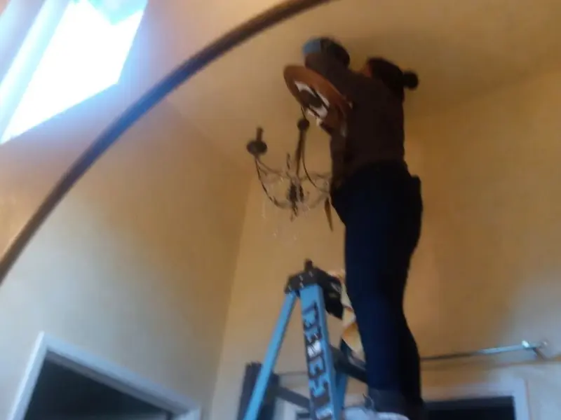 Electrician installing a chandelier in a Lake Land'Or residence